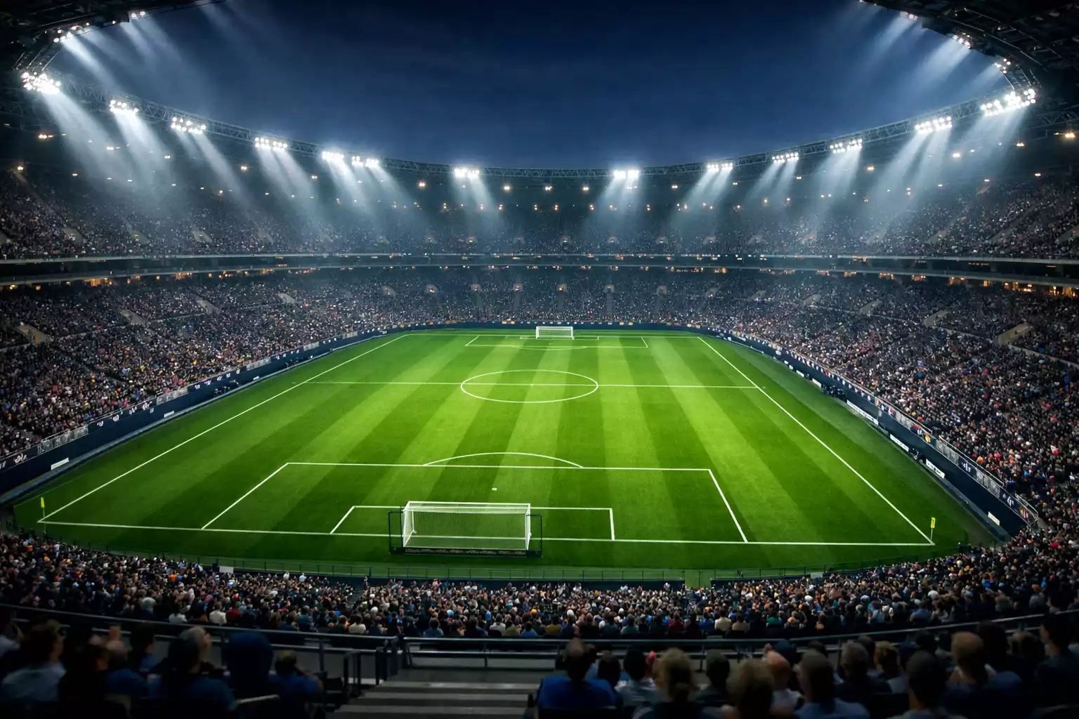 Estadio de fútbol iluminado de noche con césped verde y gradas llenas antes del inicio de un partido